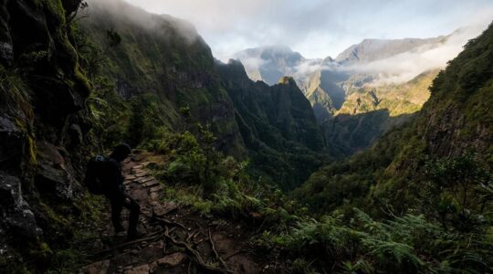 Randonneur face aux paysages volcaniques vertigineux de l'île de La Réunion avec remparts abrupts et sentiers techniques